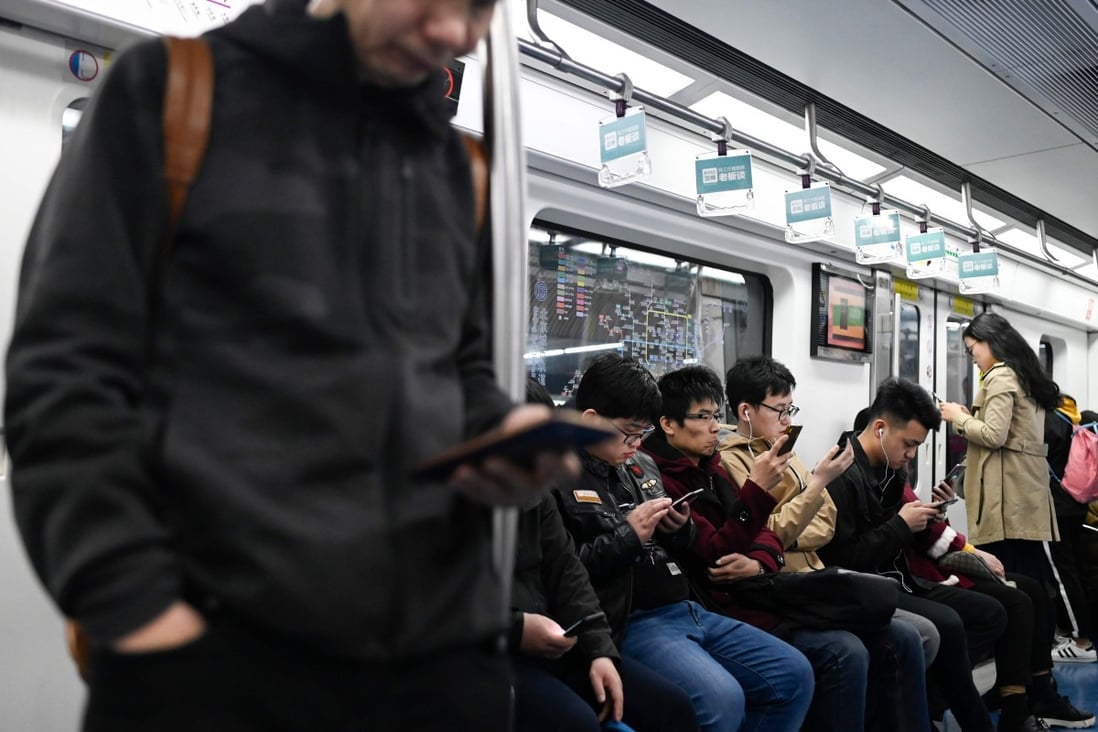 Commuters use their mobile phones as they ride on a subway in Beijing. Photo: AFP