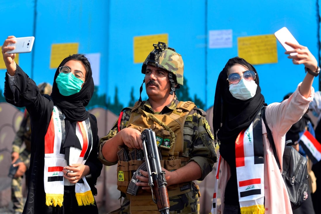 Iraqi students pose for selfies with a member of the security forces during anti-government protests in the central city of Diwaniyah on October 31. Iraq’s economy was hit hard by major internet and social media shutdowns imposed by the country’s government last year, according to a report by Top10VPN.com. Photo: AFP