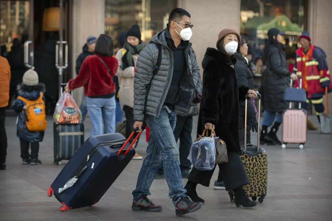 Travellers wear face masks as they walk outside the Beijing Railway Station. Photo: AP Photo