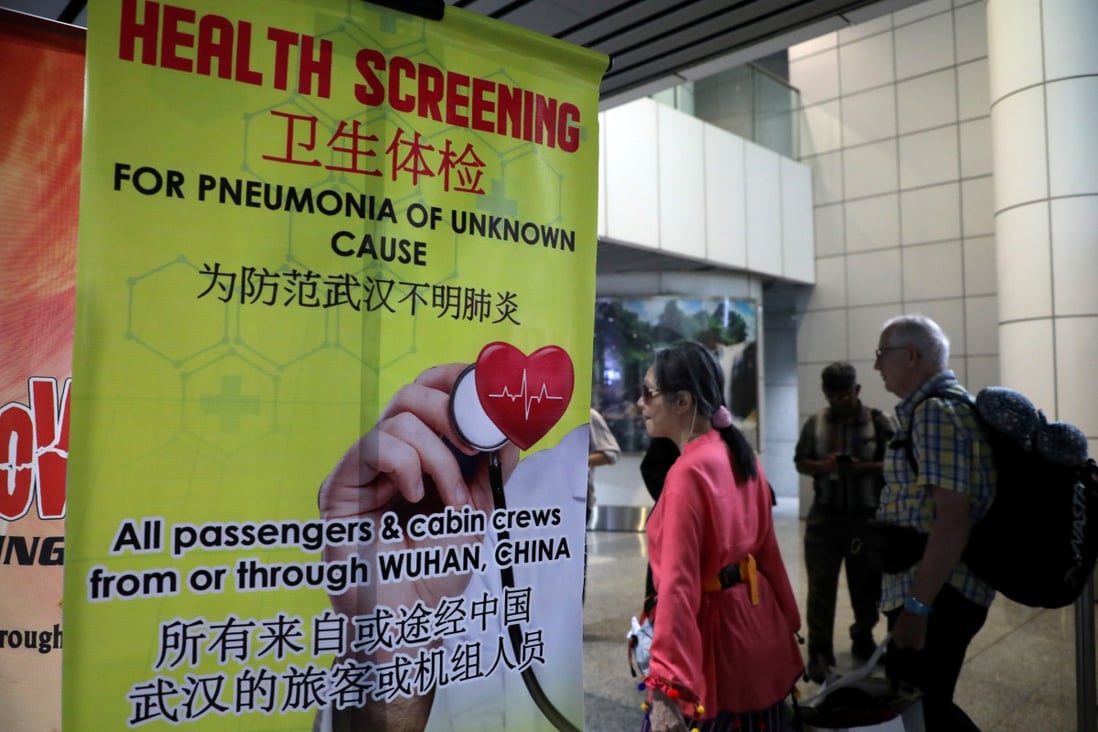 Passengers pass a banner about the Wuhan coronavirus at a thermal screening point in the international arrival terminal of Kuala Lumpur International Airport in Malaysia on Tuesday. Photo: Reuters