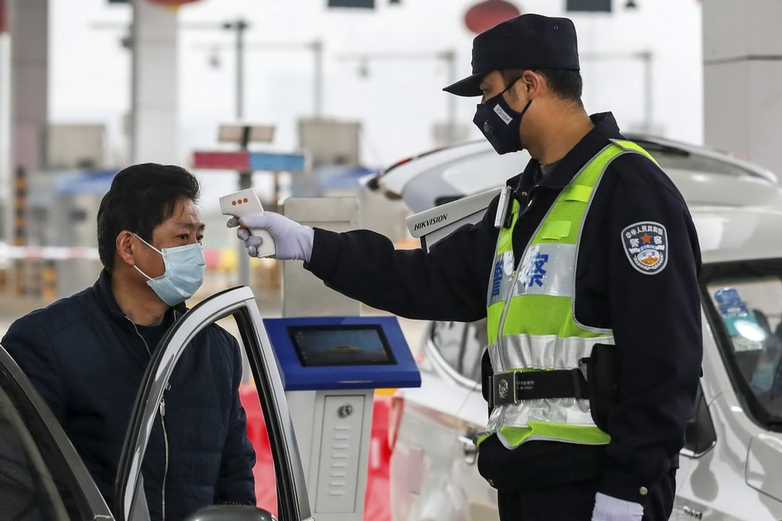 A policeman uses a digital thermometer to take a driver's temperature at a checkpoint in Wuhan, epicentre of the coronavirus outbreak. Photo: AP