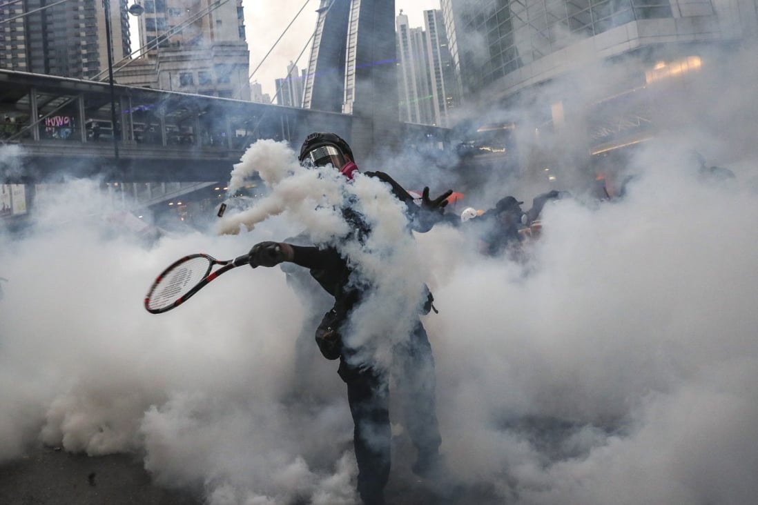 An anti-government protester uses a tennis racquet to return a canister fired by police during a clash in Tsuen Wan in August. Photo: Sam Tsang