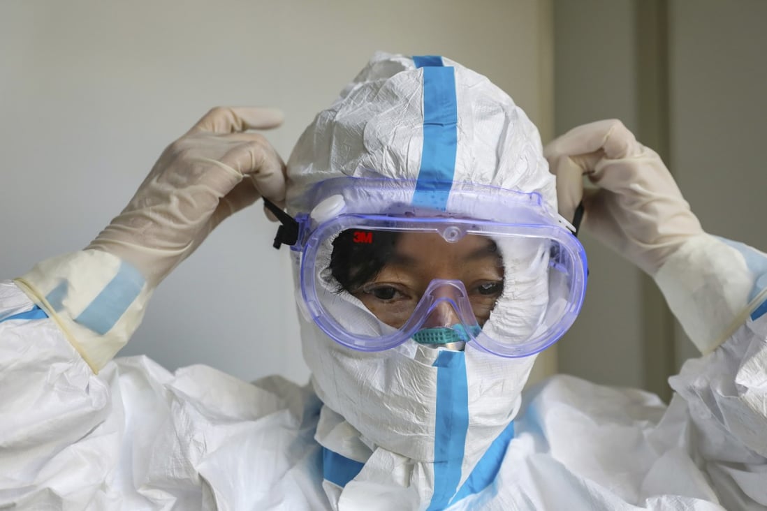 A doctor puts on a protective suit and goggles at a hospital in Wuhan. Photo: AP