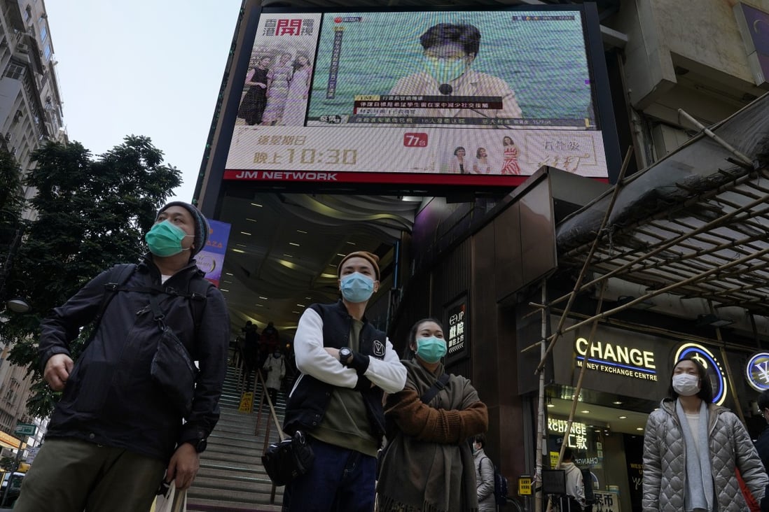 People wearing protective face masks stand in front of a screen broadcasting a speech by Hong Kong Chief Executive Carrie Lam on January 31. Photo: AP
