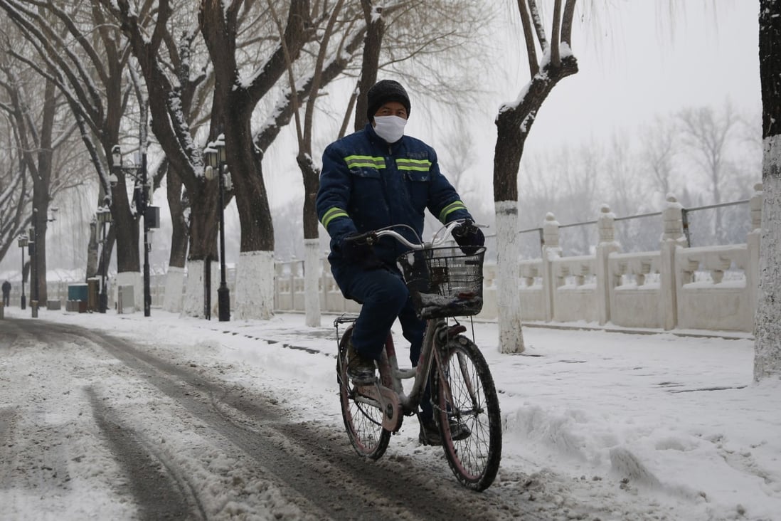 A Beijing cyclist wears a mask during a snowfall in the city on Thursday. Photo: EPA-EFE