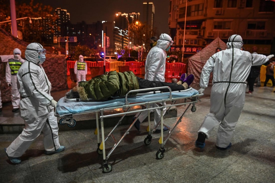 A medical staff member wearing protective clothing takes a man’s temperature at the Wuhan Red Cross Hospital. Photo: AFP