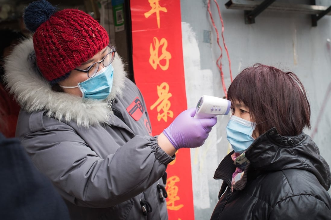 A community worker checks body temperature for a resident at a street near the Yellow Crane Pavilion in Wuhan, central China's Hubei Province, on Friday. Photo: Xinhua