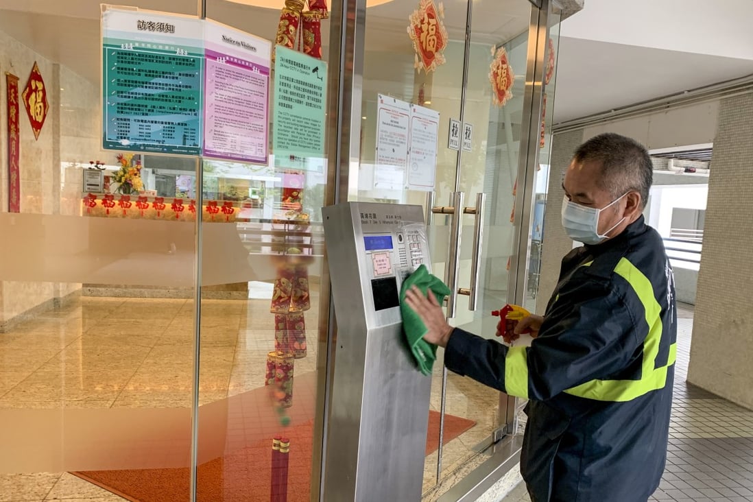 A security guard at Whampoa Garden disinfects the entry key pad outside the building. Photo: Minnie Chan