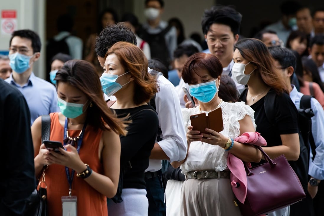 People wearing protective masks stand in line for a temperature check outside an office building in Singapore. Photo: Bloomberg