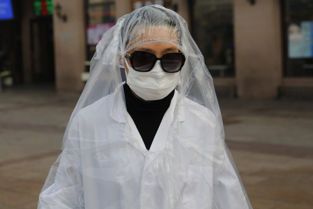 A passenger wearing a protective mask covers her body with plastic bags as protection from the coronavirus at a Beijing railway station on Tuesday. Photo: EPA-EFE
