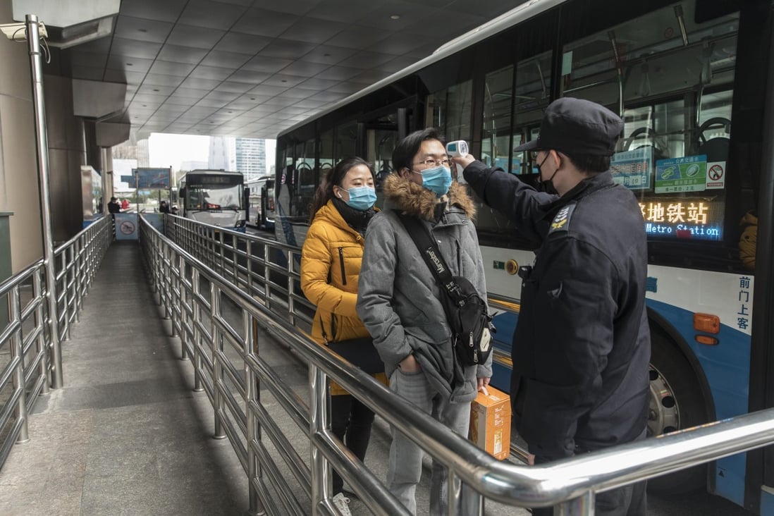 An official checks the temperature of passengers at a bus terminal in Shanghai. Photo: Bloomberg
