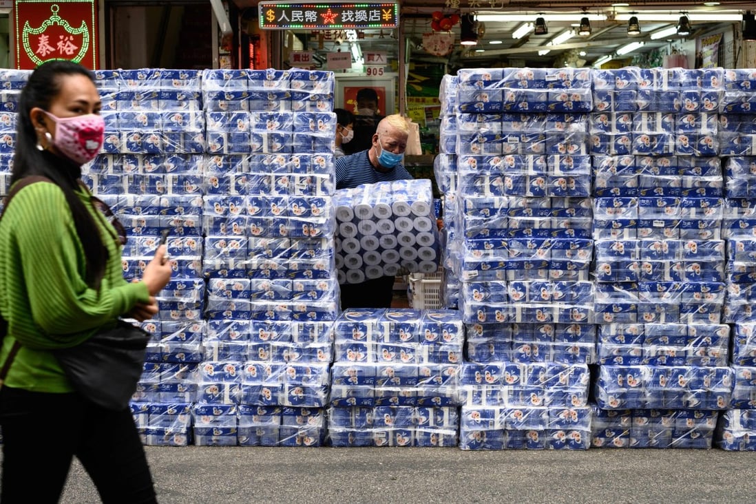 A woman wearing a protective face mask walks past stacks of toilet paper for sale in the Tsuen Wan district of Hong Kong on February 8. The Hong Kong government has rejected calls to use emergency legislation to crack down on price-gouging retailers amid a citywide shortage of face masks. Photo: AFP