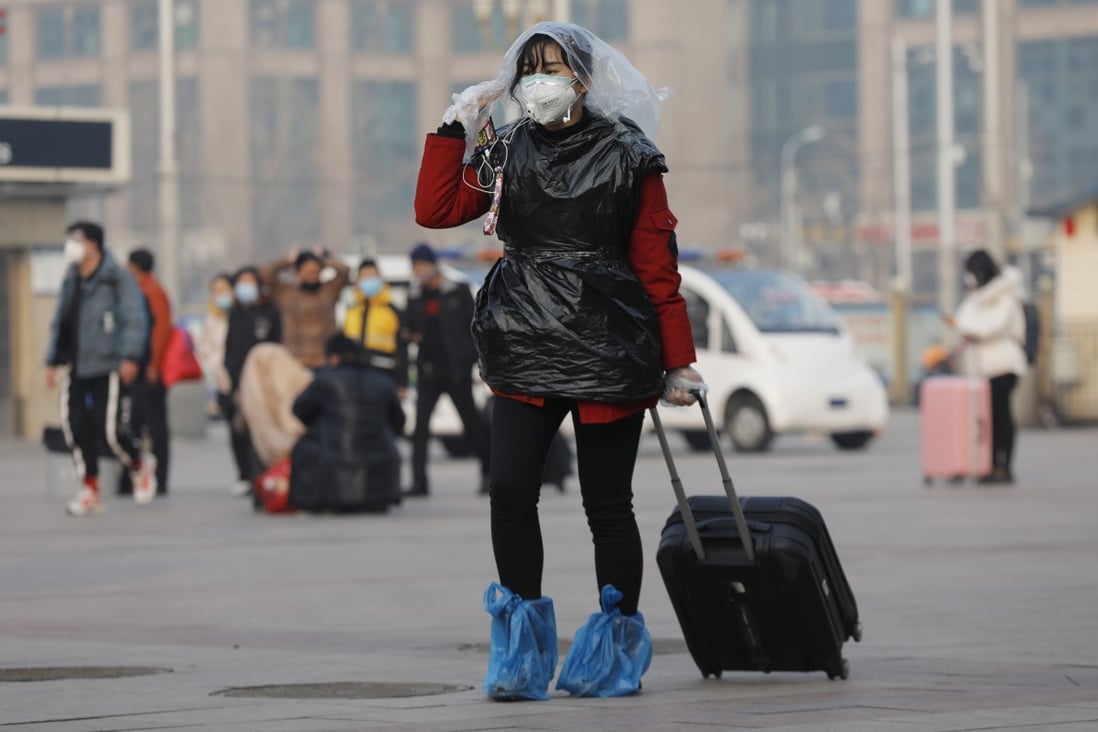 A passenger at a Beijing railway station covers her head and body with plastic bags for added protection against the coronavirus. Photo: EPA-EFE