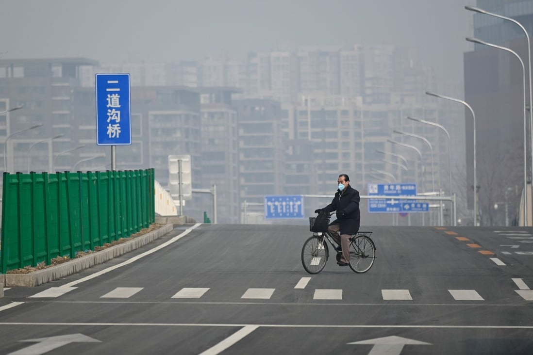 A man wearing a face mask rides his bicycle along an empty street in Beijing, which has been shrouded in heavy smog this week. Photo: AFP