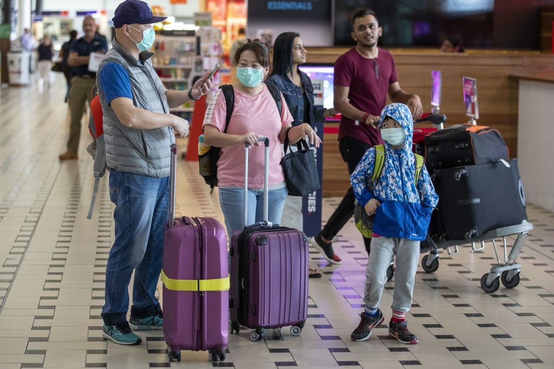 Passengers wearing face masks arrive at Brisbane International Airport. Photo: AFP