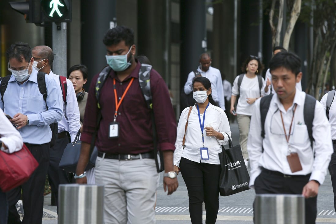 Commuters wearing protective masks walk through the Marina Bay business district in Singapore on Wednesday. Photo: Bloomberg