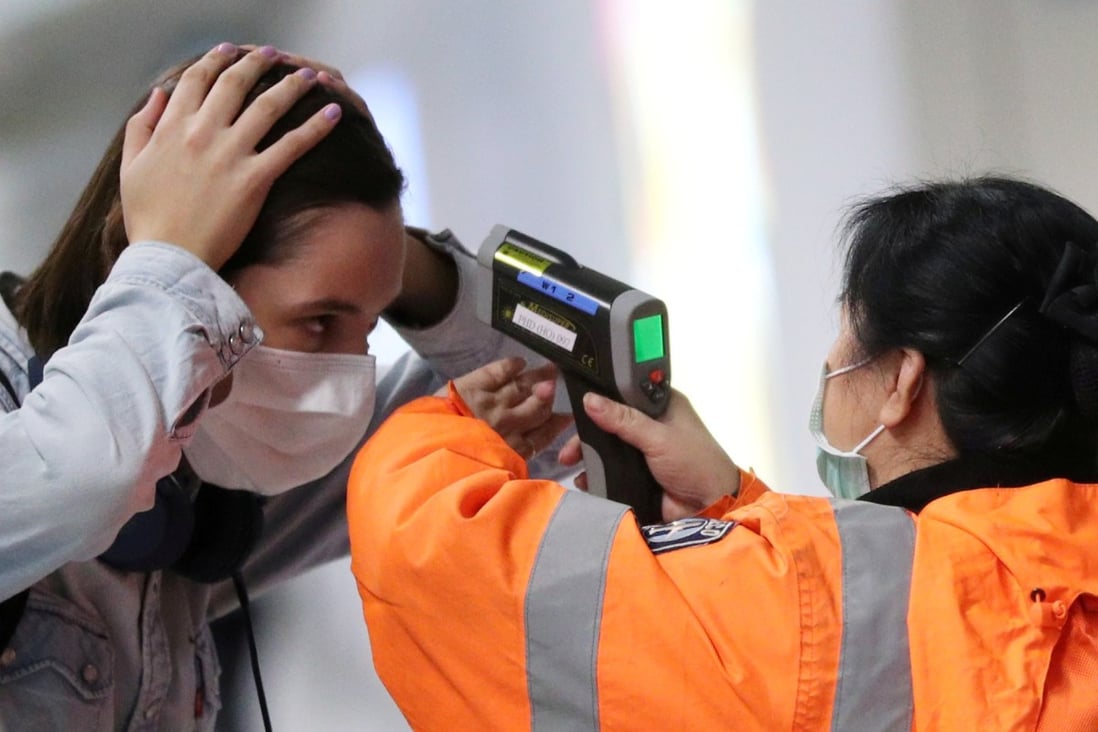A passenger has her temperature taken at Hong Kong International Airport. The city’s anti-government protests and the Covid-19 outbreak are proving to be catalysts for life decisions among its residents. Photo: Reuters
