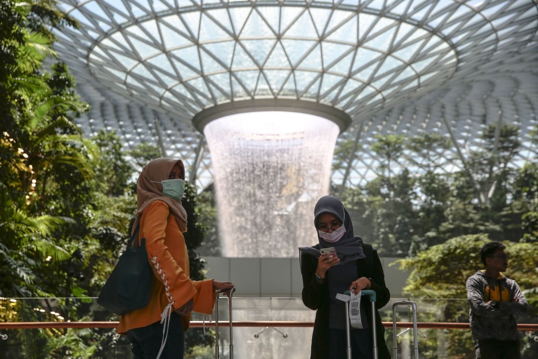 People wearing protective face masks stand near the Rain Vortex at the Jewel Changi Airport mall in Singapore. The Ministry of Health has reported 75 coronavirus cases. Photo: EPA-EFE
