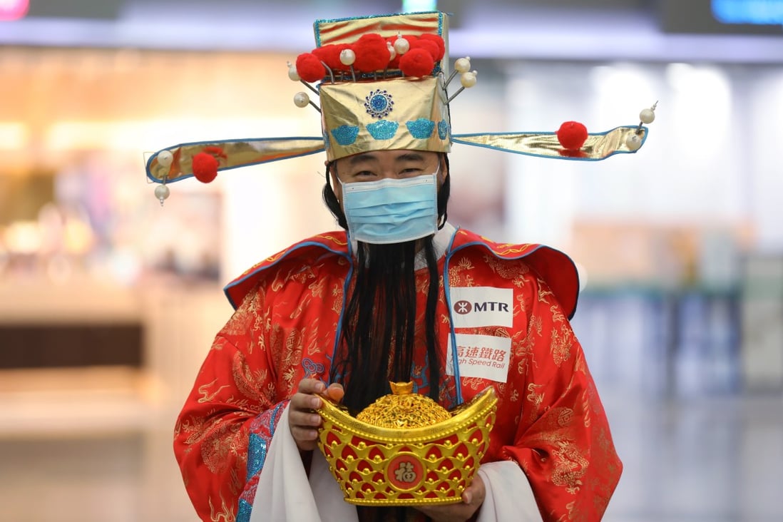 An MTR employee dressed as the god of wealth wears a mask at West Kowloon Station to avoid contracting the Covid-19 disease. The region’s wealthy investors have been going about their business as usual even the outbreak began to spread. Photo: Winson Wong