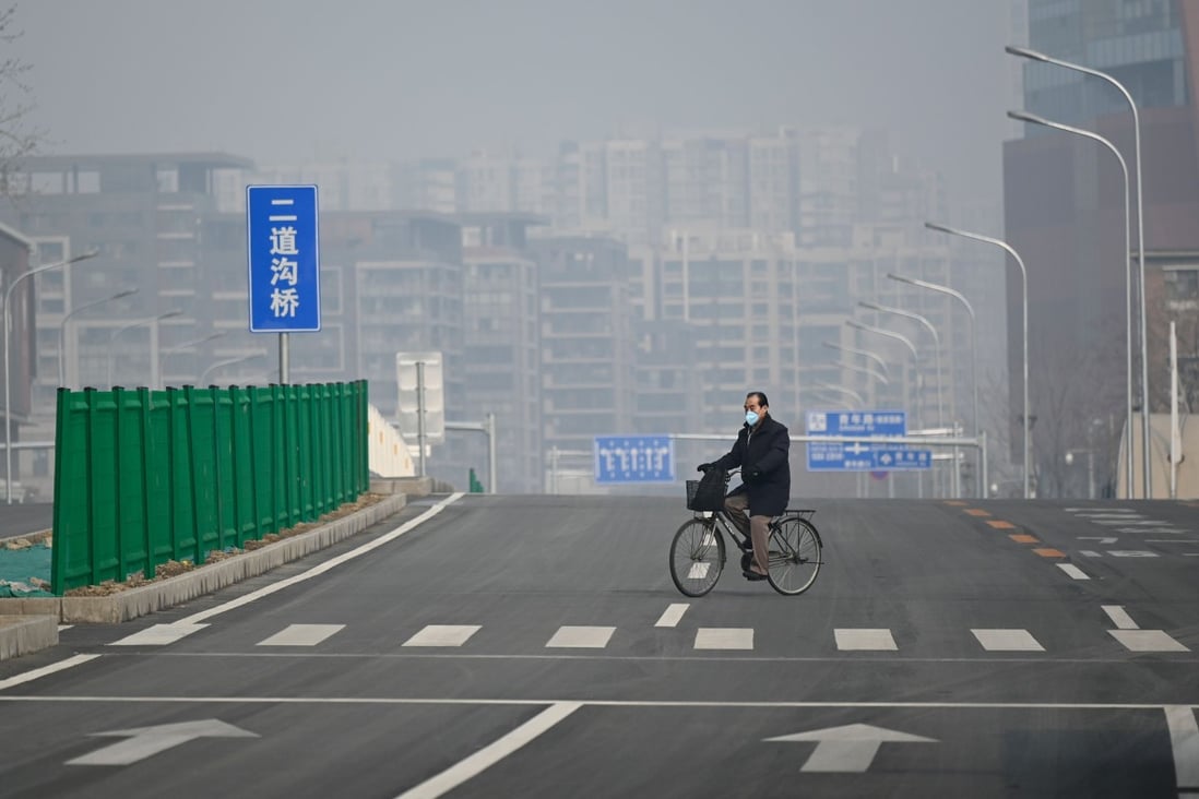 A man wearing a face mask rides his bicycle along an empty street in Beijing on February 12. Photo: Agence France-Presse