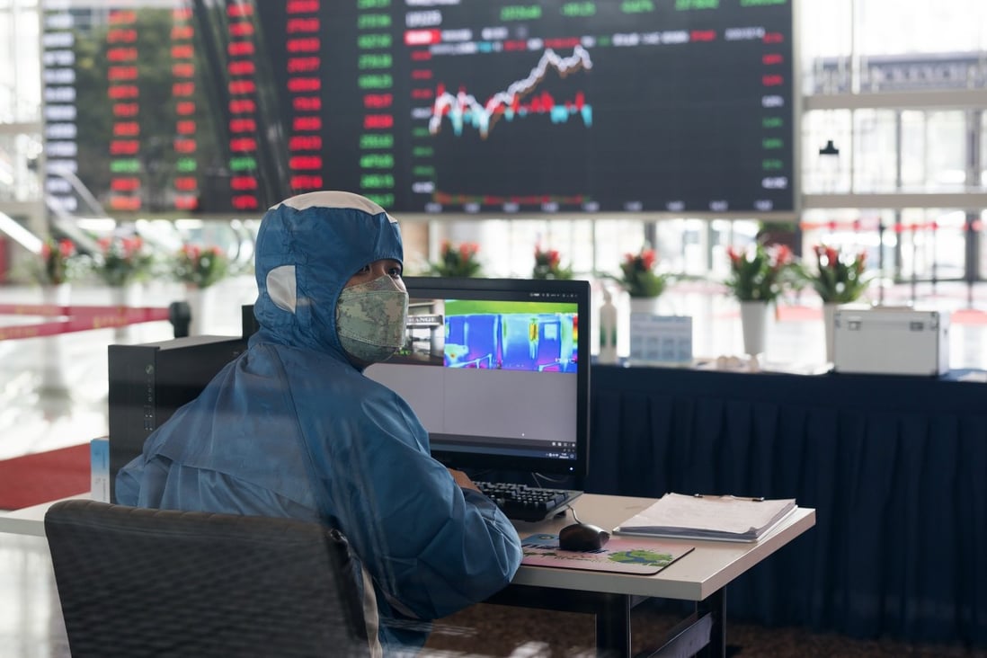 A worker wearing a protective suit reacts in front of an infrared temperature machine in the lobby of the Shanghai Stock Exchange building in Shanghai on February 14. Asian shares mostly fell Friday as investors turned cautious on the coronavirus outbreak. Photo: AP