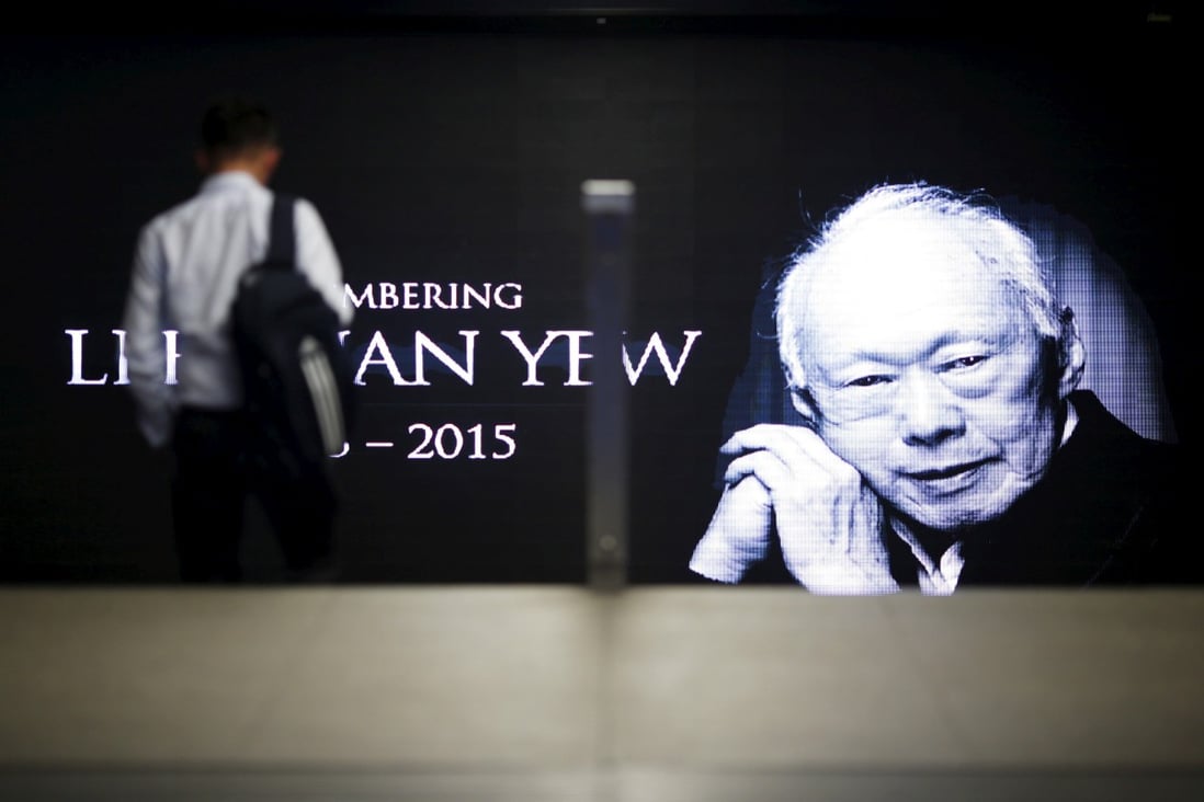A commuter passes a signboard bearing an image of Lee Kuan Yew, the first prime minister of Singapore. Photo: Reuters