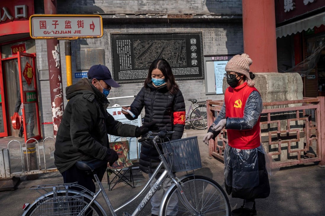Community volunteers wearing protective face masks and gloves take the temperature of a man on a street in Beijing. Photo: AFP