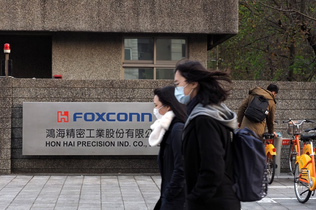 People wearing face masks walk past a Foxconn Technology Group building in New Taipei City, Taiwan, on February 18. The world’s largest electronics contract manufacturer said respiratory disease scientist Zhong Nanshan will act as its chief coronavirus prevention adviser. Photo: EPA-EFE