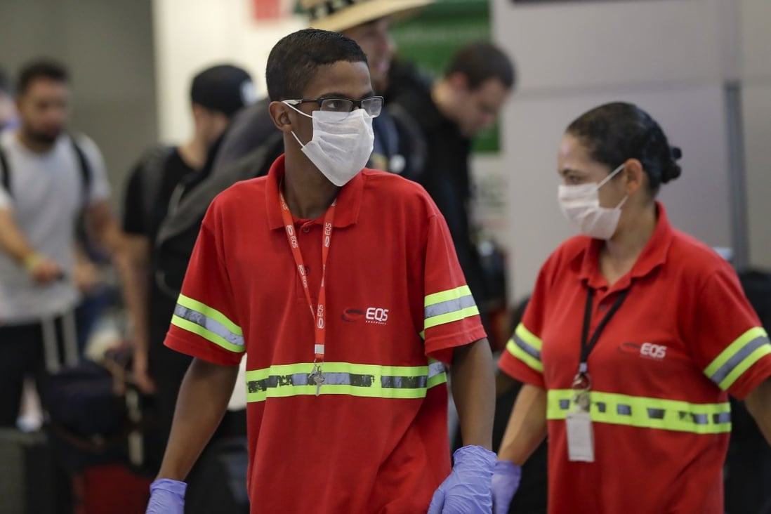 Airport employees wear masks as a precaution against the spread of the coronavirus as they work at Brazil’s Sao Paulo International Airport on Wednesday. Photo: AP