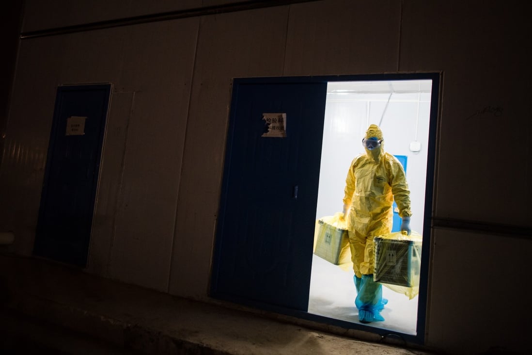 Liu Senbo carries sealed boxes containing samples collected from Covid-19 patients at the Leishenshan Hospital in Wuhan, Hubei province. Clad in protective gear, he fetches samples twice a day and sends them to a virus testing centre. Photo: Xinhua
