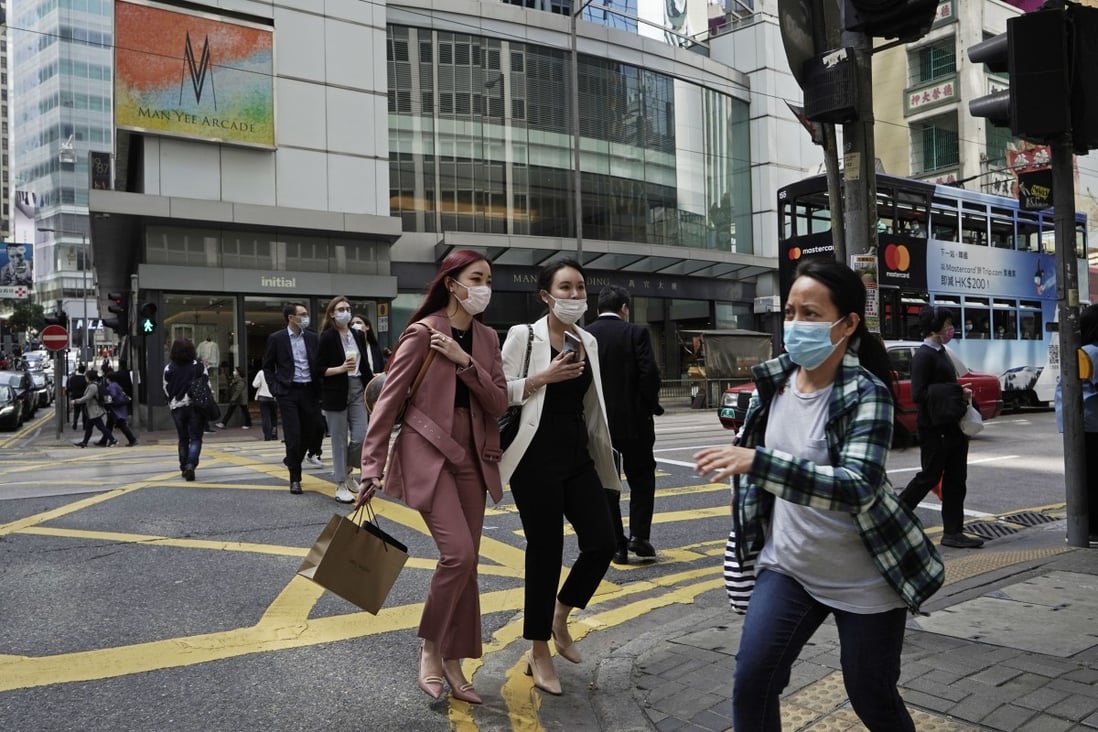 People wearing masks, walk across a street in Hong Kong on February 24. The coronavirus outbreak has struck fears in the market as property sales came to near a standstill. Photo: AP Photo