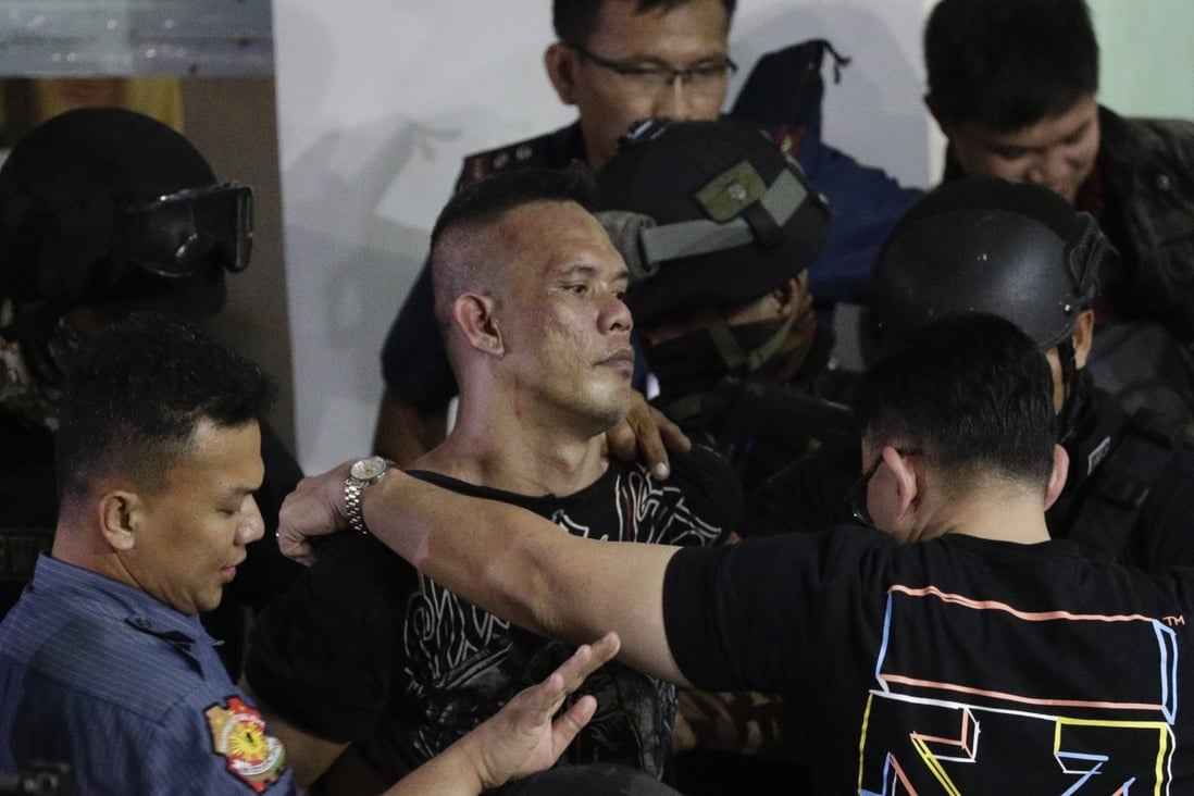 Archie Paray, centre, is escorted by police shortly after releasing all his hostages at the V-Mall in Manila on Monday. Photo: AP