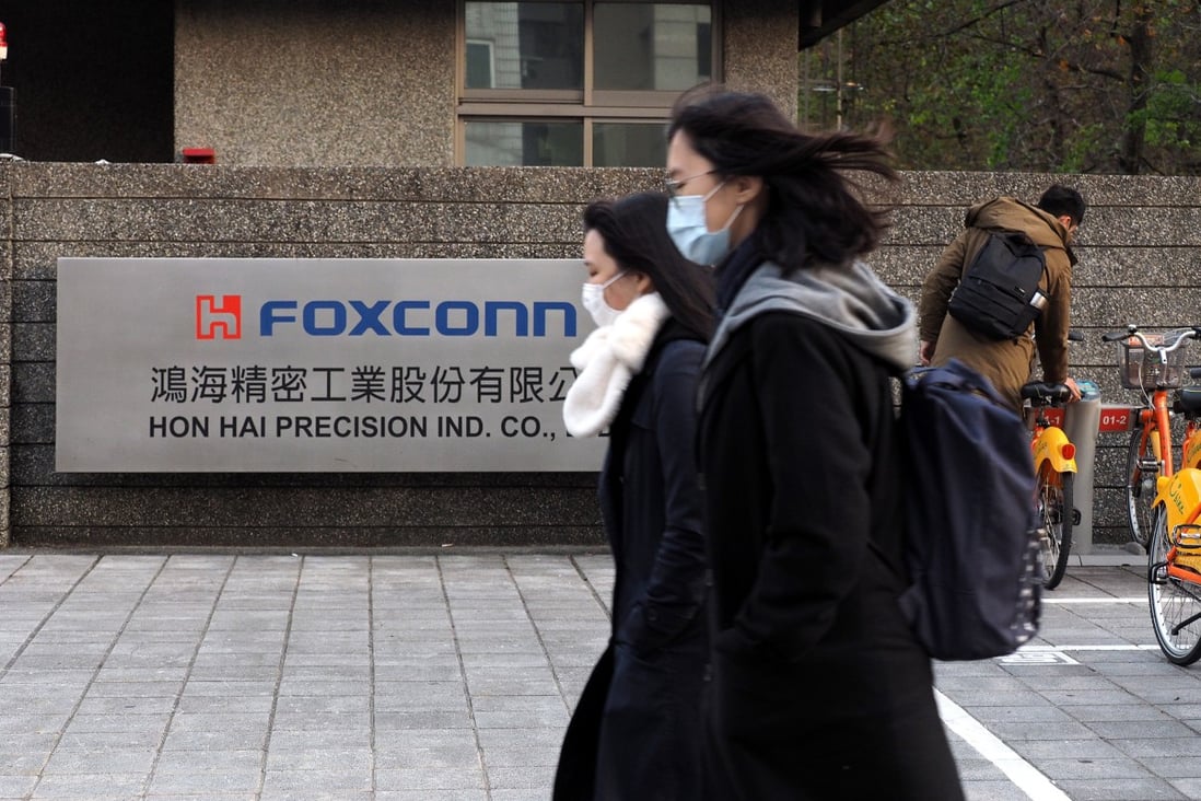 People wearing face masks walk past a building of Foxconn Technology Group in New Taipei City, Taiwan, on February 18. Photo: EPA-EFE