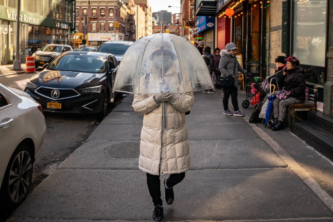 A person wears a protective mask while walking with an umbrella in New York’s Chinatown neighbourhood. Photo: Bloomberg