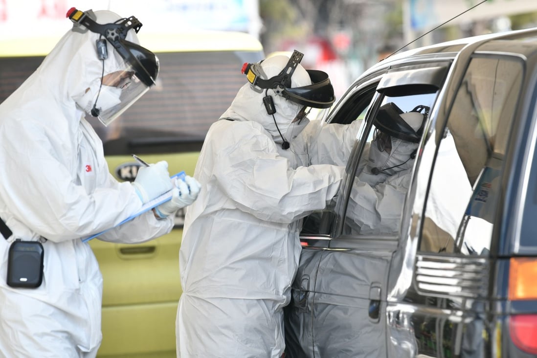 Medical workers wearing protective gear take samples from a driver with suspected coronavirus symptoms at a ‘drive-through’ test facility in South Korea. Photo: AFP