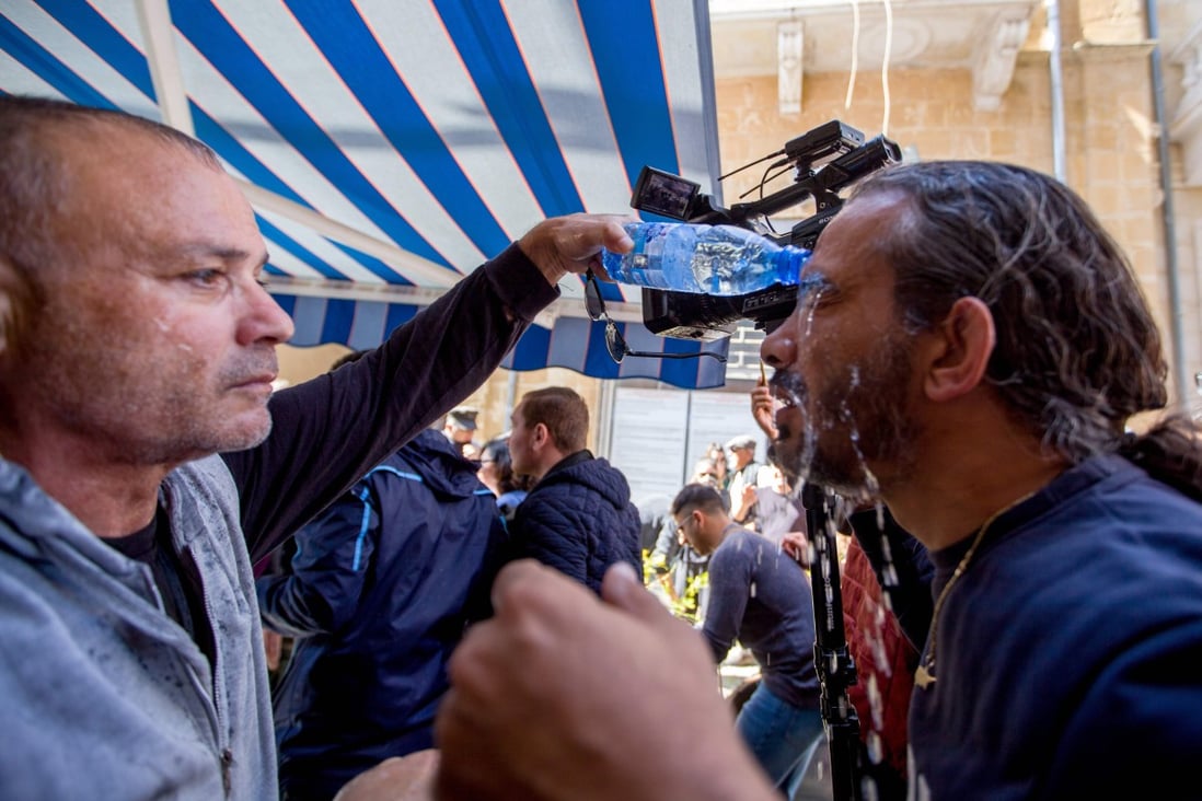 A protester helps a cameraman who was affected by tear gas amid clashes between Cypriot police and Turkish protesters. Photo: AFP