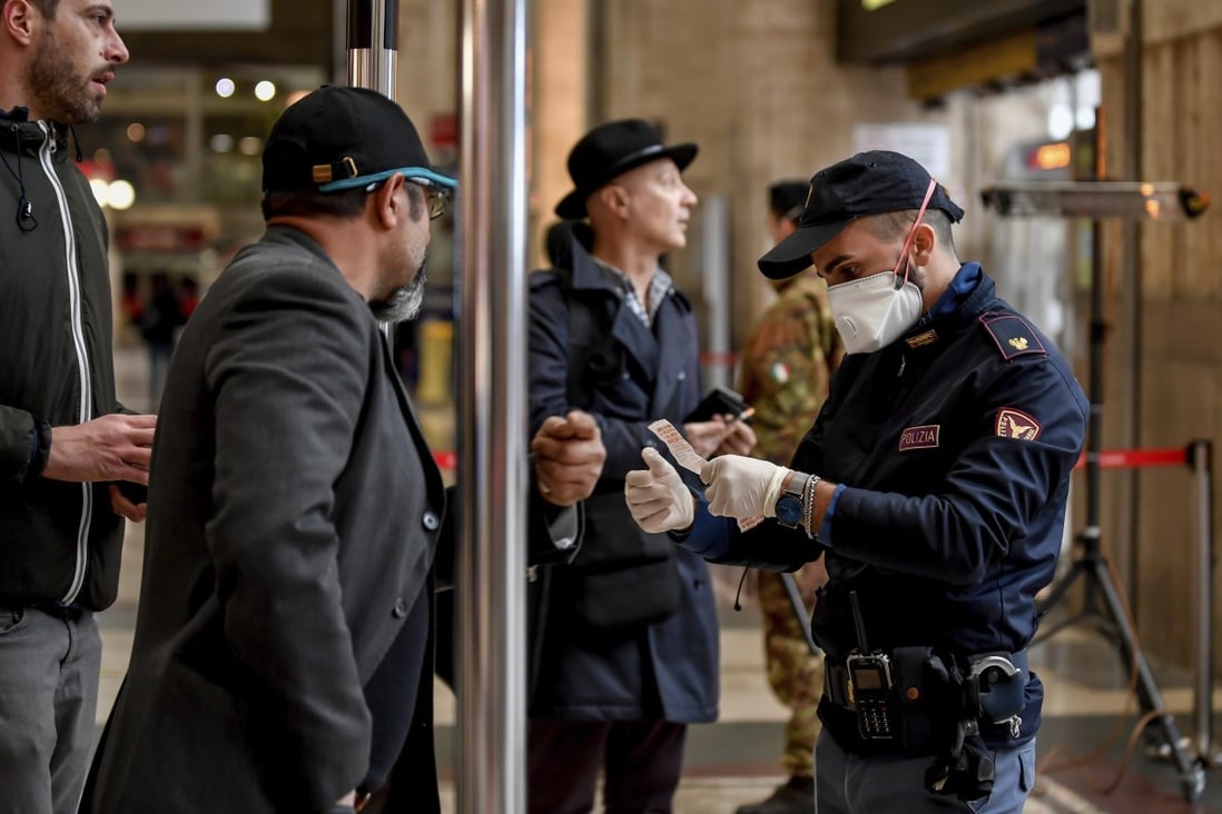 A police officer checks passengers leaving from Milan railway station. Photo: AP