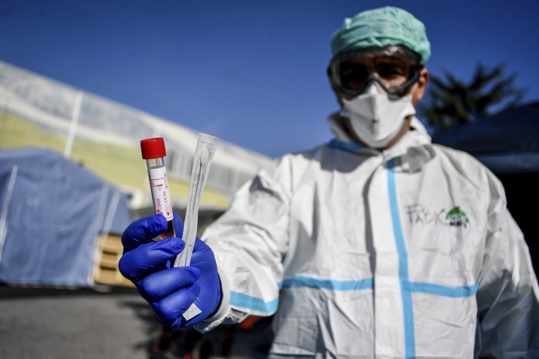 A medical worker holds out a test kit outside an emergency facility in Brescia, northern Italy on Tuesday. The nation is the worst-hit after China. Photo: AP