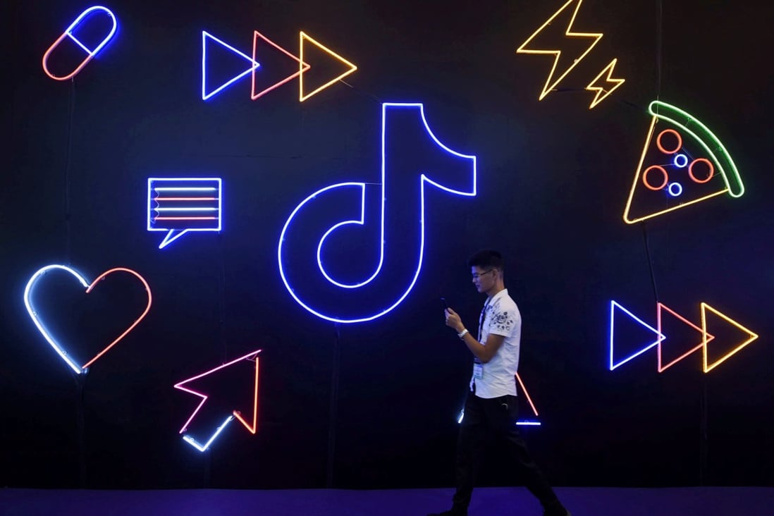 A man holding a smartphone walks past a sign for ByteDance's global hit TikTok, the short video app that has Douyin as its Chinese counterpart, at an event in Hangzhou, Zhejiang province, in October of last year. Photo: Reuters