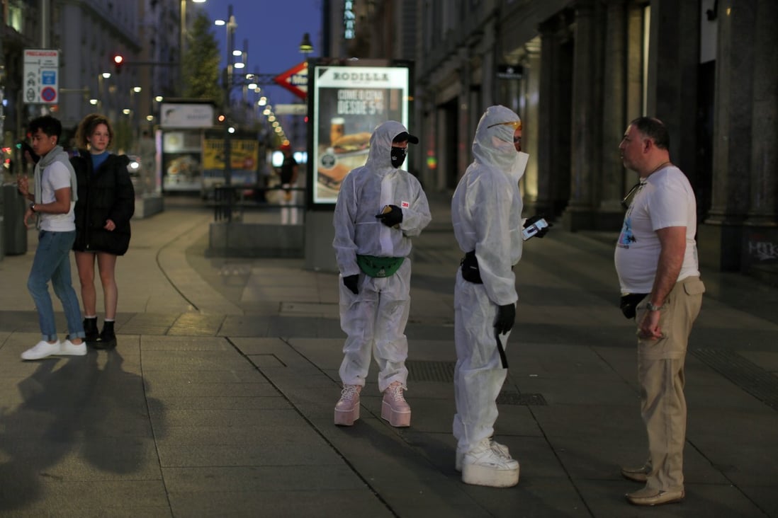 People wearing protective clothes talk with a man at the Gran Via avenue in downtown in Madrid. Photo: AP Photo