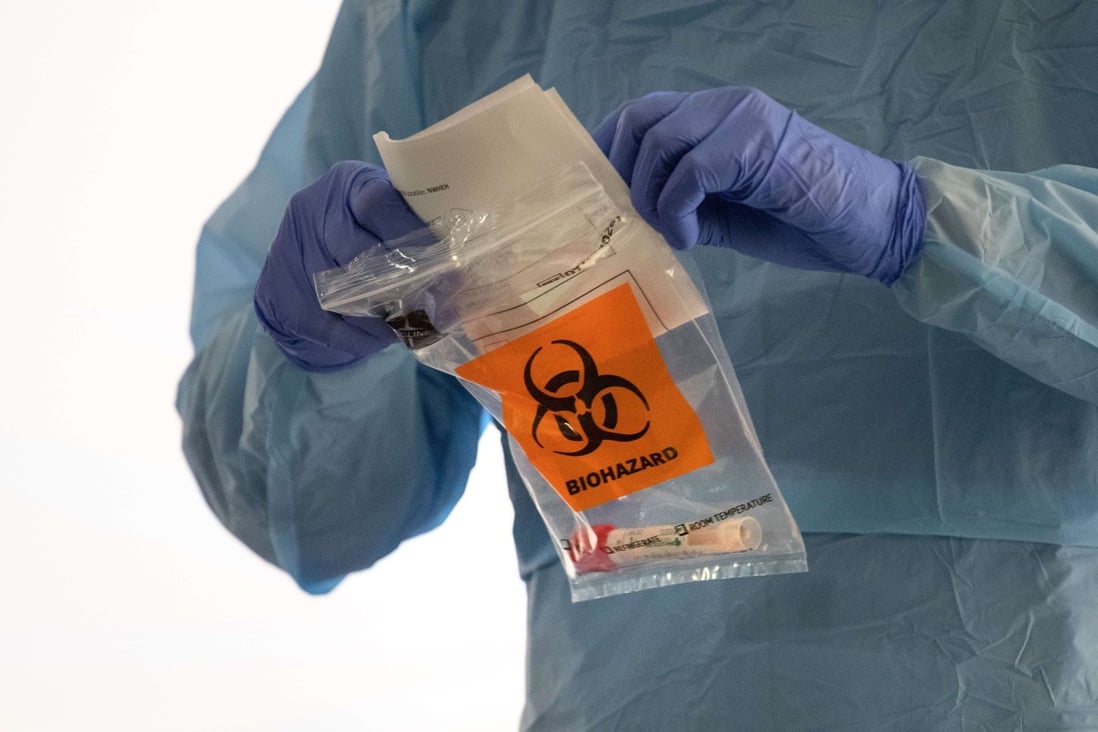 A nurse in protective clothing handles a potentially infected coronavirus swab at a drive-by testing centre in Seattle on Friday. Photo: AFP