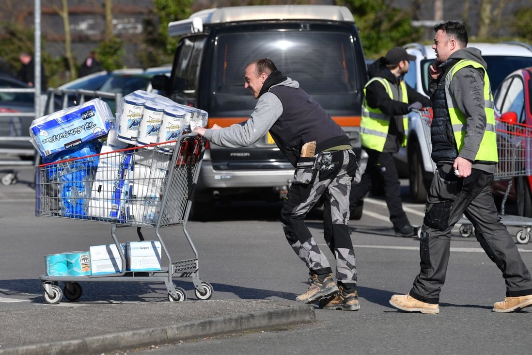 A customer leaves a supermarket in Liverpool with a trolley full of toilet paper on Monday. Photo: AFP