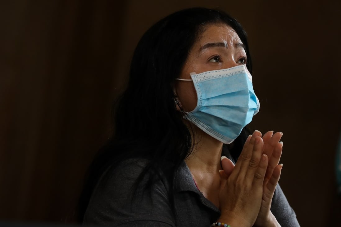 A woman wearing a mask prays inside a church south of Manila last week. Photo: EPA