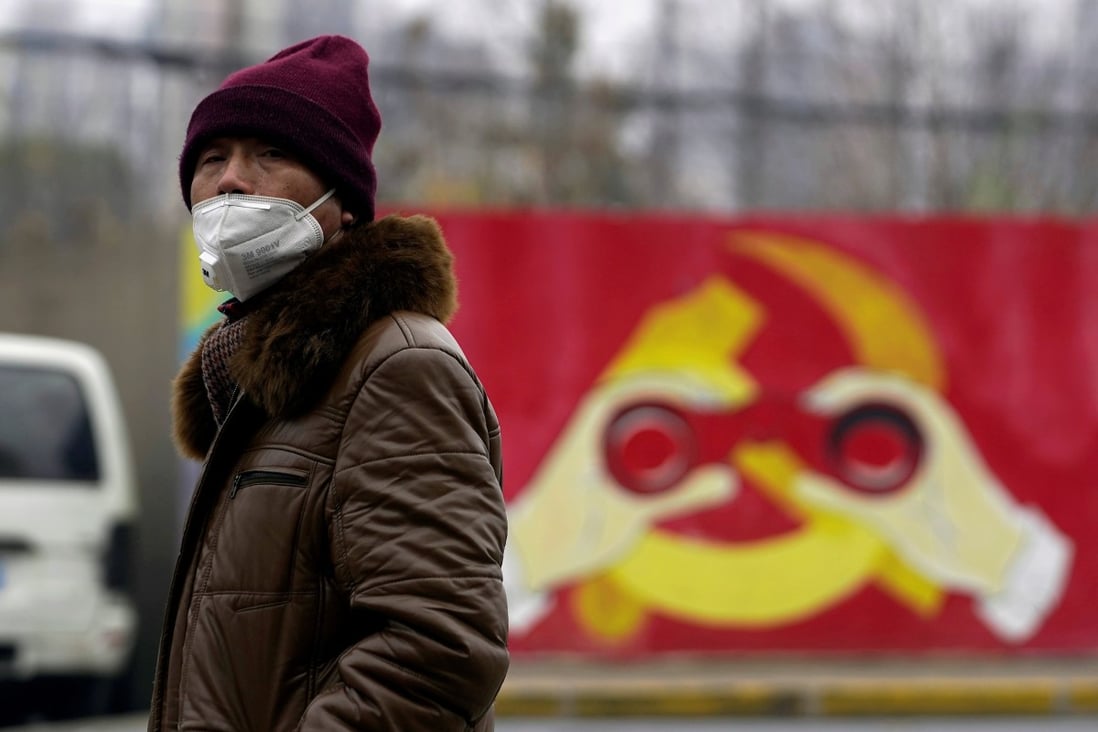 A man wearing a mask walks past a mural showing a modified image of the Communist Party emblem in Shanghai. Photo: Reuters