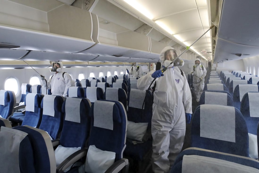 Workers in protective gear disinfect a plane bound for New York Incheon International Airport in South Korea, as the pandemic shifts westwards. Photo: AP