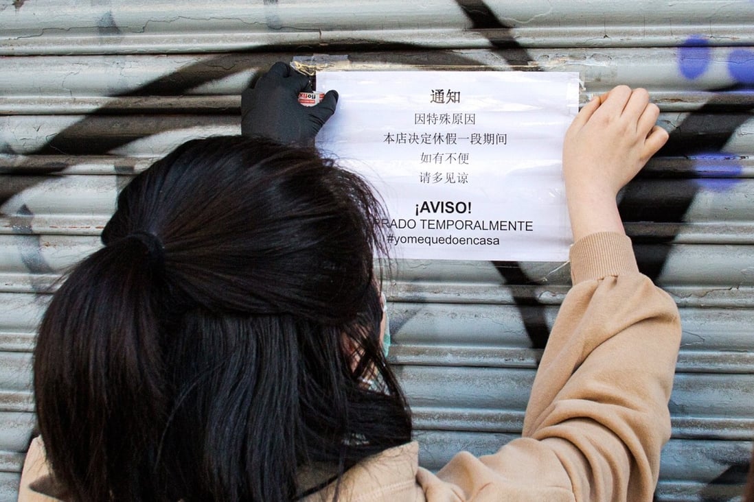 A Chinese woman puts up a closed notice at her business in Spain, along with an exhortation to citizens not to leave their homes during the coronavirus outbreak. Photo: Antolin Avezuela