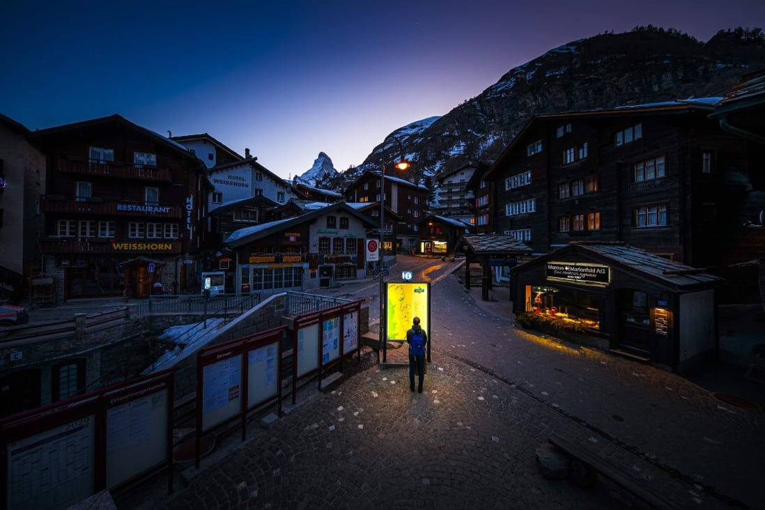 A pedestrian looks at an illuminated map on the empty streets of the Alpine resort of Zermatt, on March 18, after the Swiss government declared a state of emergency to combat the coronavirus pandemic. Photo: AFP