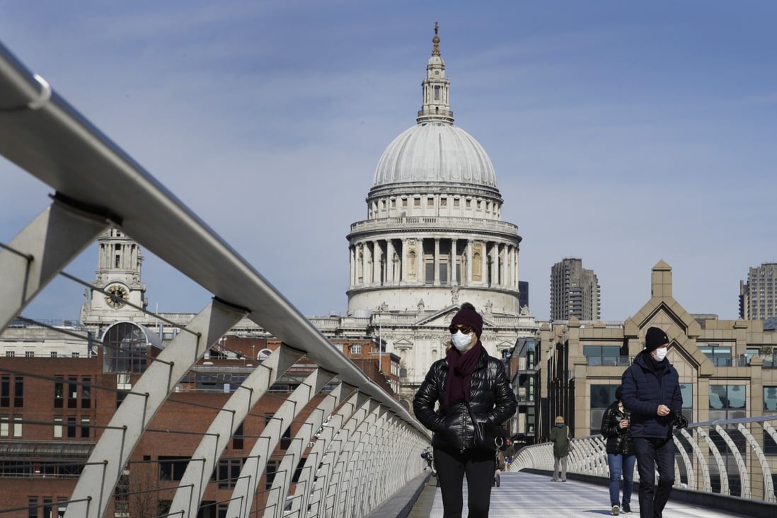 People wear masks as they walk over Millennium Bridge near St Paul's Cathedral in London on Sunday. Photo: AP