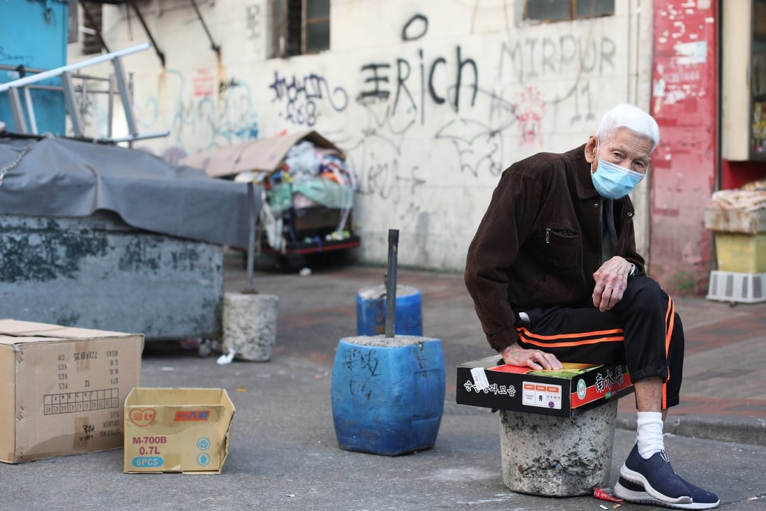 An elderly man sits on a cardboard box in a street in Sham Shui Po. Photo: Xiaomei Chen