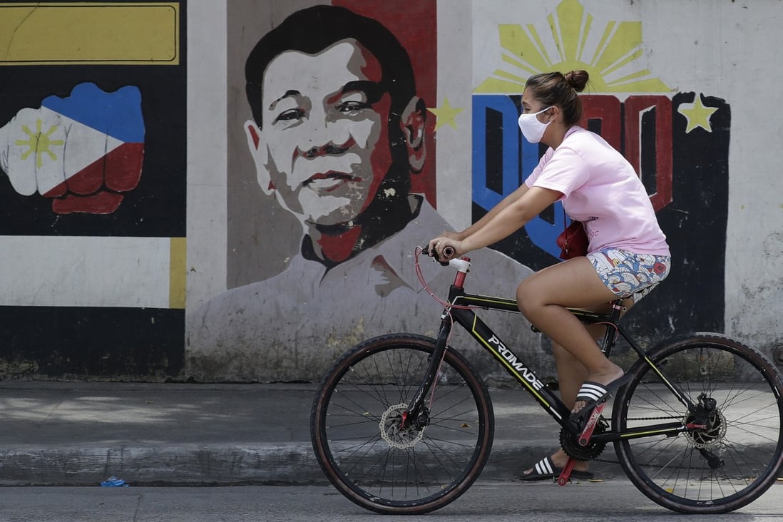 A cyclist rides past a mural of Philippine President Rodrigo Duterte in Manila on March 20, 2020. Photo: AP